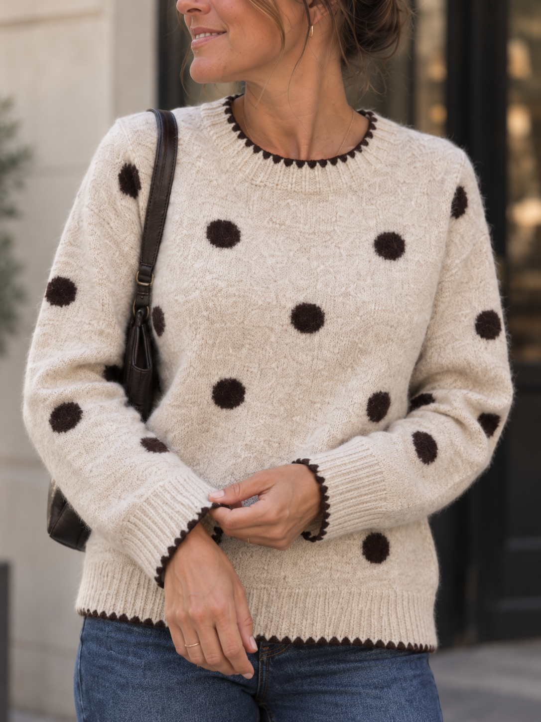 Detailansicht des cremefarbenen Strickpullovers mit braunen Punkten und Kontrastkanten