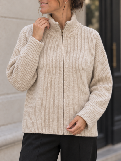 Detailansicht der cremefarbenen Strickjacke mit Rippenstrick und Reißverschluss